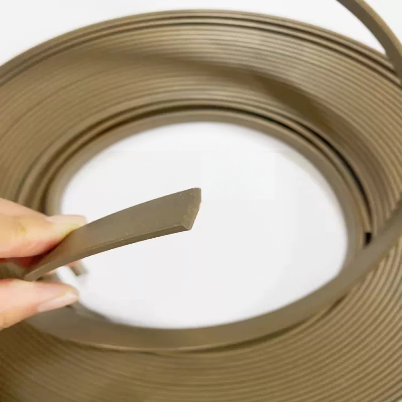 A hand holding the cut end of a bronze filled PTFE guide strip