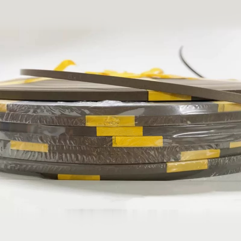 Stacked bronze filled PTFE wear-strip coils viewed from the edge