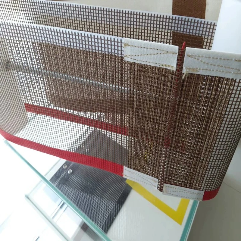 Brown open mesh belt sections with reinforced edges on a workshop surface