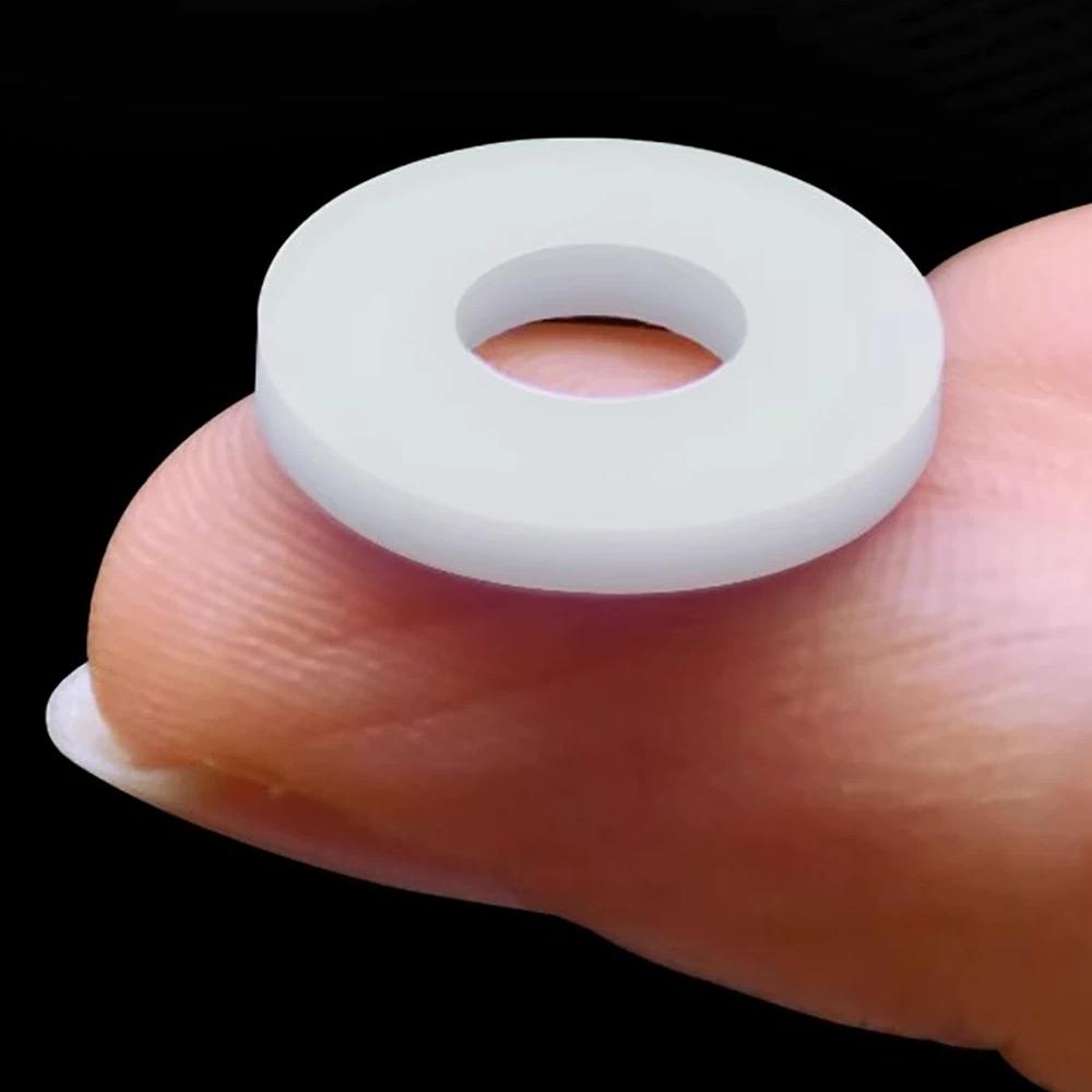 A white PTFE flat sealing washer resting on a fingertip