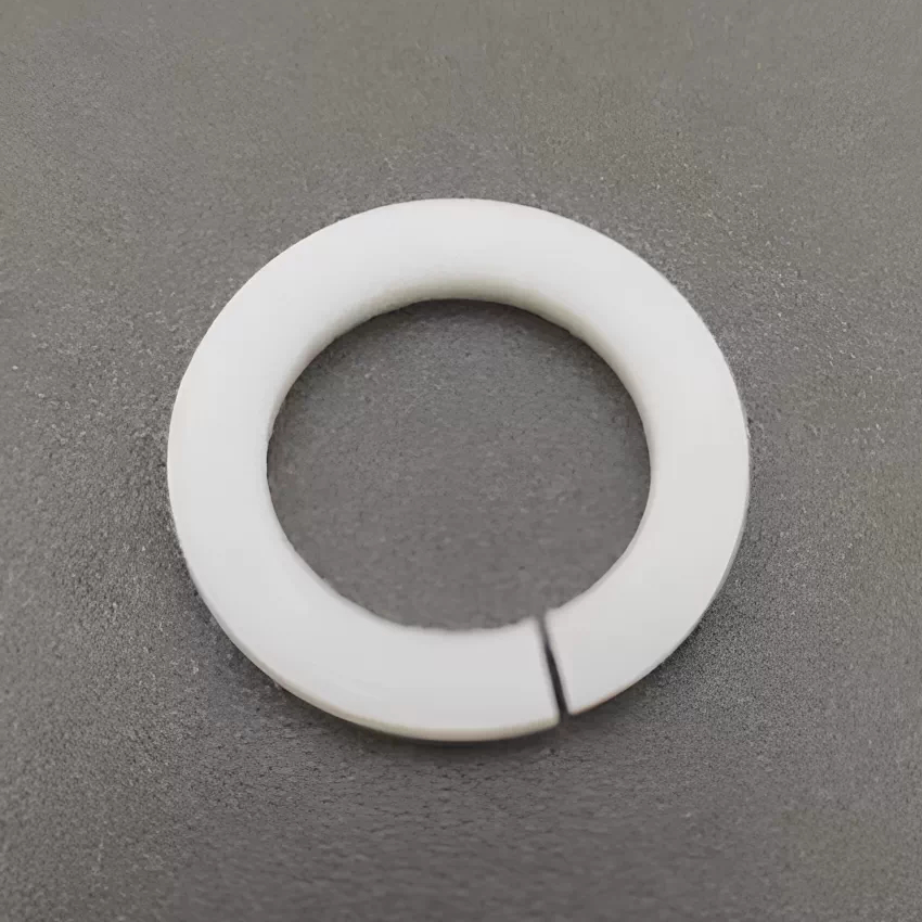 A white PTFE split ring viewed from above on a textured surface